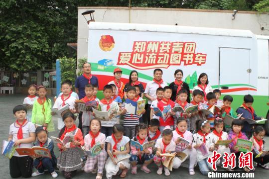 小学生与志愿者们在流动图书车前合影留念。　刘正华 摄