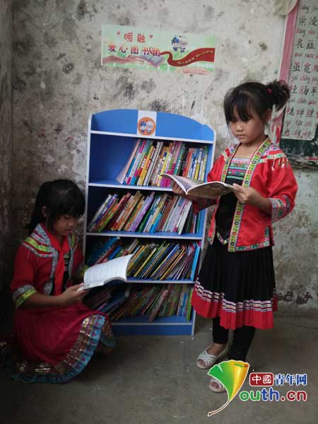 郑州大学融水服务队在高马小学捐建4座“暖融”爱心图书角。图为高马小学学生在图书角旁阅读课外书。