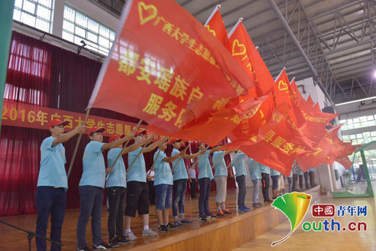 广西举办2016年西部计划志愿者出征仪式。图为与会领导为西部计划志愿者服务队授旗。=