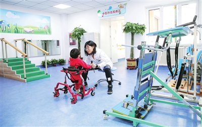 图为残疾儿童正在康复训练室进行康复训练。